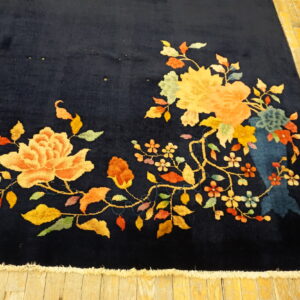 Navy rug featuring bright yellow and peach flowers and green leaves on aged plank flooring.