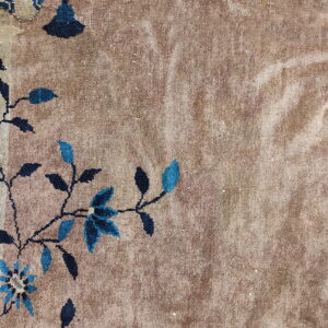 Textured tan rug field featuring detailed dark blue floral and vine elements along the border.