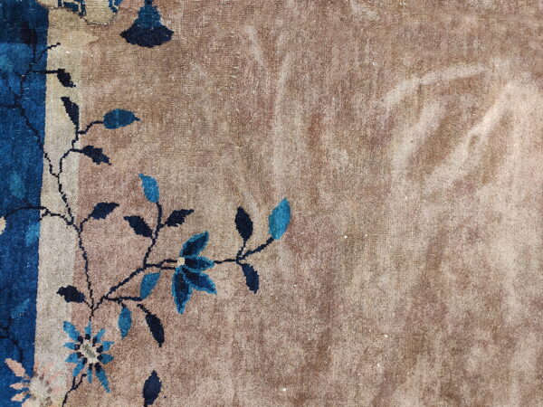 Textured tan rug field featuring detailed dark blue floral and vine elements along the border.