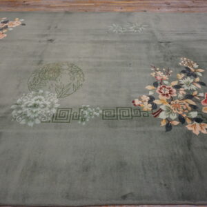 Sage green area rug with colorful floral sprays and geometric patterns on a rustic wooden floor.