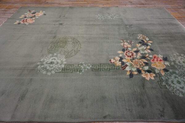 Sage green area rug with colorful floral sprays and geometric patterns on a rustic wooden floor.