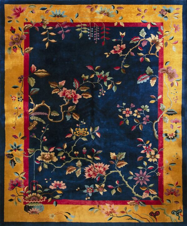 A deep blue rug with a gold border and intricate multi-colored floral and vine patterns.