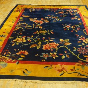 Navy blue area rug with a detailed multicolored floral pattern and a wide golden yellow border on wood flooring.