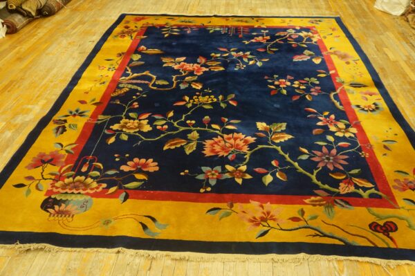 Navy blue area rug with a detailed multicolored floral pattern and a wide golden yellow border on wood flooring.