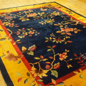Botanical rug featuring colorful vines on a deep blue field with a wide mustard yellow border on wood planks.