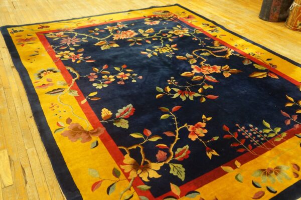 Botanical rug featuring colorful vines on a deep blue field with a wide mustard yellow border on wood planks.