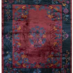 Red central field rug with a teal border and multicolored floral vine pattern.