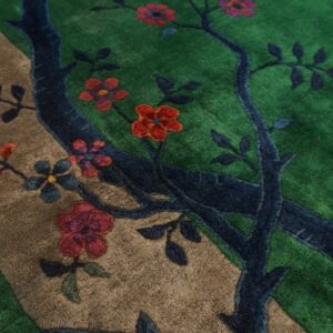 High-pile rug detail showing a blue tree, colorful flowers, and a tan path on a green background.