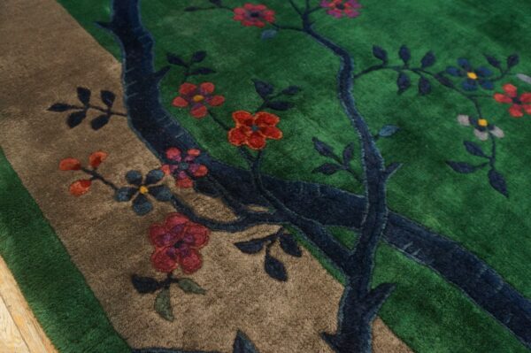 High-pile rug detail showing a blue tree, colorful flowers, and a tan path on a green background.