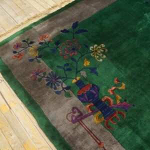 Emerald green high-pile rug border featuring multicolored flowers and a vase on light wood floor.