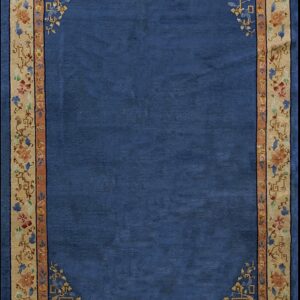 Deep blue rug featuring a wide tan border decorated with multi-colored floral and geometric designs.