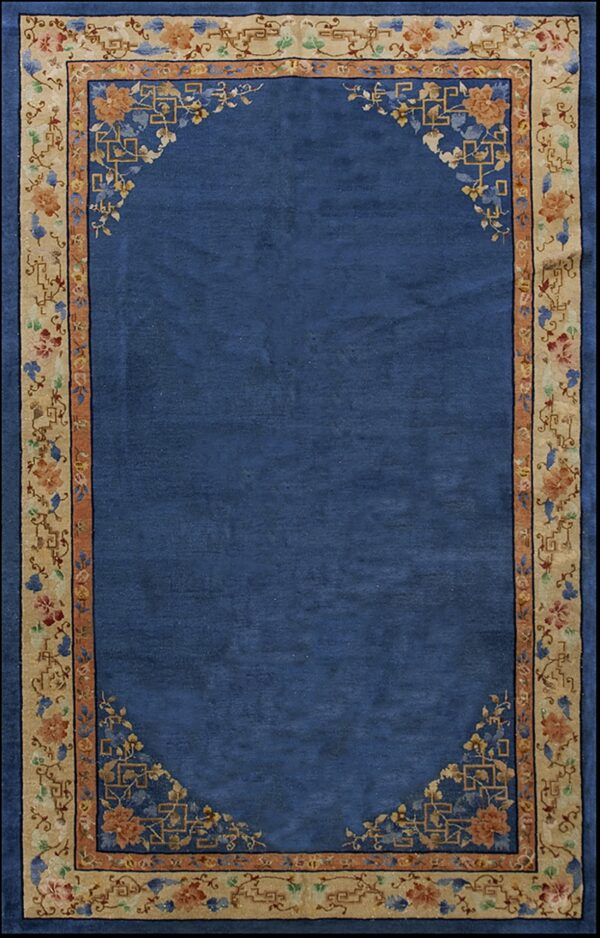 Deep blue rug featuring a wide tan border decorated with multi-colored floral and geometric designs.