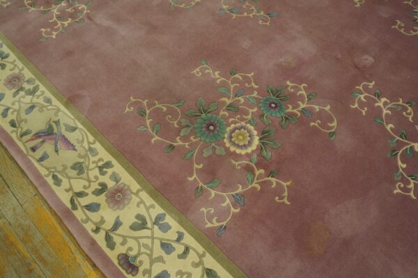 Muted mauve high pile rug with floral and bird motifs resting on distressed hardwood floors.