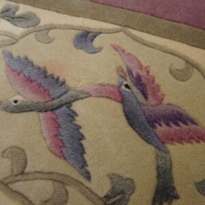 Cream, plush rug featuring sculpted pink, purple, and blue birds and gray vine designs.