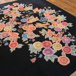 Large black rug with a multicolored floral bouquet pattern lies on natural hardwood floors.
