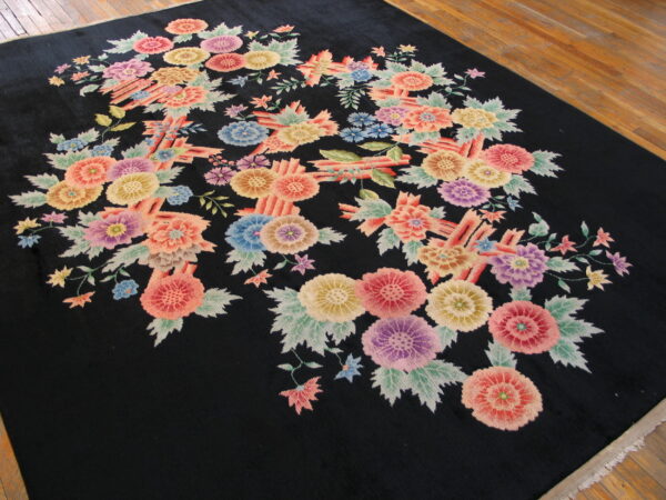 Large black rug with a multicolored floral bouquet pattern lies on natural hardwood floors.