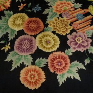 A plush black rug features large, colorful floral bouquets detailed in yellow, red, purple, and sage green.