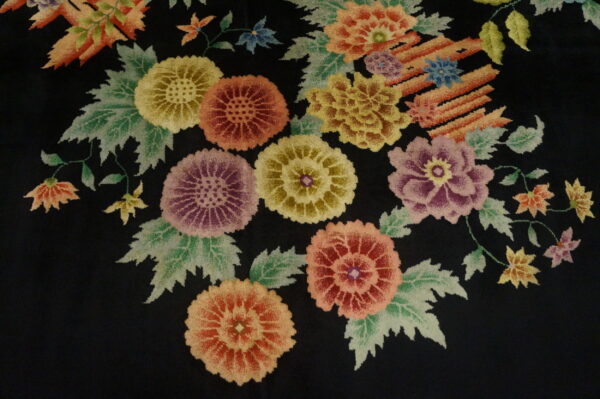 A plush black rug features large, colorful floral bouquets detailed in yellow, red, purple, and sage green.