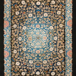 Intricate floral rug featuring a dense ivory pattern on a black and blue field with pink and teal borders.