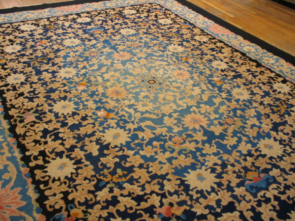Ornate floral rug with navy, cerulean, and beige colors resting on light brown hardwood flooring.