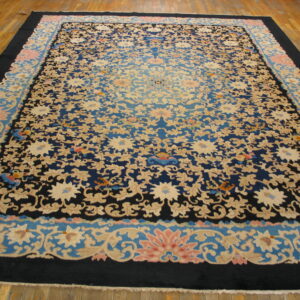 Navy and beige floral rug with pink accents and a shaded blue center displayed on wood planks.