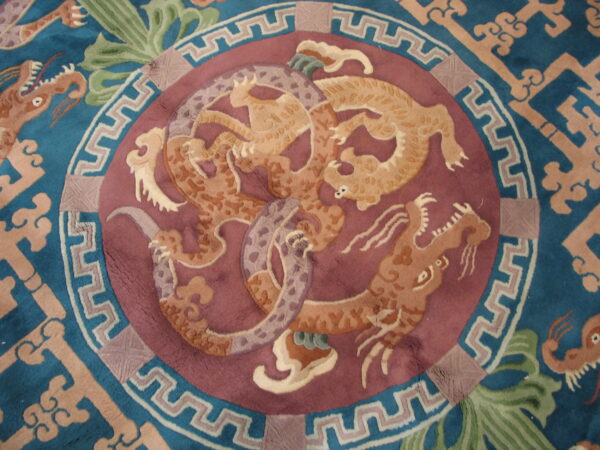 Teal rug featuring a mauve medallion with intricate tan dragon figures and a geometric border.