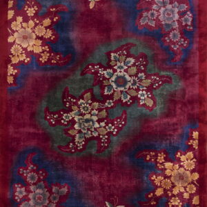 Deep red rug with large floral medallions and butterflies patterned over mottled navy and olive green sections.