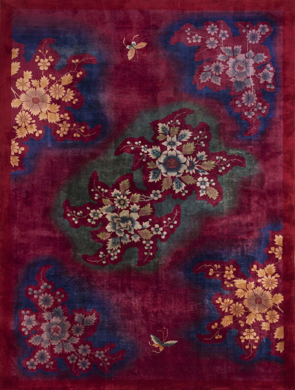 Deep red rug with large floral medallions and butterflies patterned over mottled navy and olive green sections.