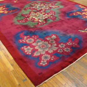 Vibrant magenta rug displaying large floral patterns in blue, green, and pale yellow on hardwood floors.