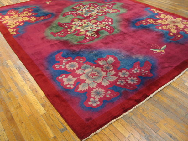 Vibrant magenta rug displaying large floral patterns in blue, green, and pale yellow on hardwood floors.