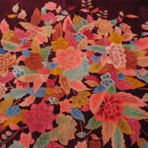 Multicolor floral pattern on a deep burgundy rug, featuring dense pink, green, blue, and gold motifs.