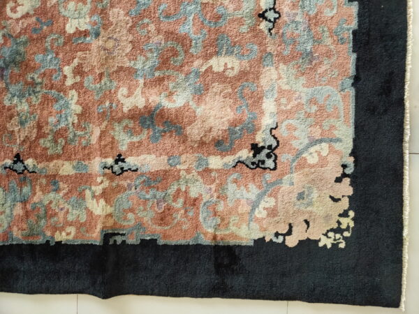 Textured high-pile rug featuring dusty rose and blue floral patterns surrounded by a wide black border.