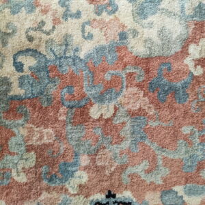 Plush rug texture featuring an intricate pattern of cream, blue, and terracotta tones.