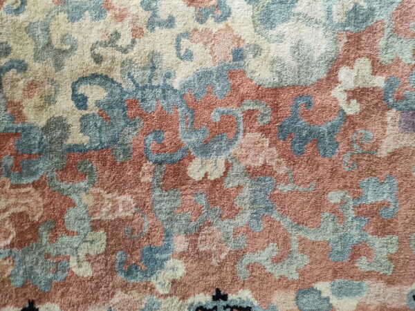 Plush rug texture featuring an intricate pattern of cream, blue, and terracotta tones.