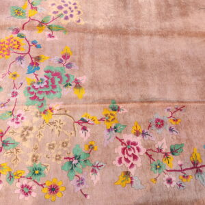 Muted pink rug with colorful floral vines and leaves in pink, teal, yellow, and purple across the surface.