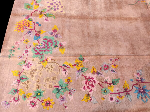 Muted pink rug with colorful floral vines and leaves in pink, teal, yellow, and purple across the surface.