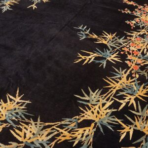 Circular black rug featuring a stylized pattern of gold bamboo shoots and coral blossoms on wood flooring.