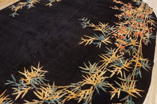 Circular black rug featuring a stylized pattern of gold bamboo shoots and coral blossoms on wood flooring.