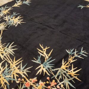 Dark pile rug featuring gold and teal bamboo and coral floral motifs on wood flooring.
