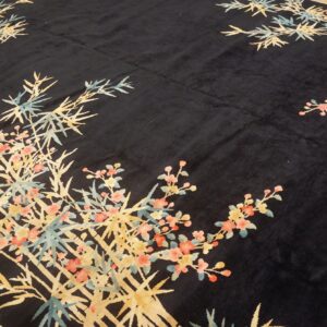 A thick black pile rug detailed with light blue and golden bamboo and pink flowering branches.
