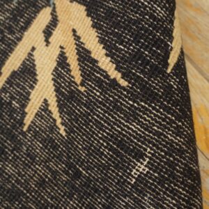 Woven rug detail showing black, tan, and teal geometric patterns on light wooden floor.