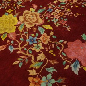 Deep burgundy rug featuring an all-over floral pattern with yellow, tan, blue, and pink accents.