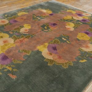 Deep green floral rug displaying large yellow, purple, and peach flowers on wooden planks.