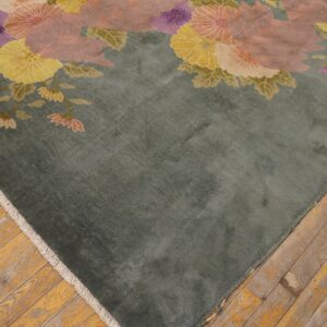 A soft sage rug with large pink, purple, and yellow floral patterns rests on distressed wood floors.
