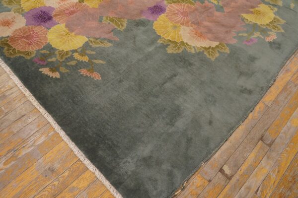A soft sage rug with large pink, purple, and yellow floral patterns rests on distressed wood floors.