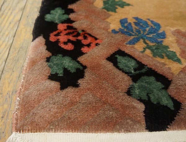 High-pile rug corner featuring bold blue, coral, green, and black floral patterns on distressed wood.