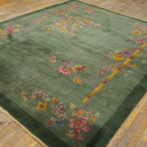 Green pile rug with bright pink and yellow floral patterns and a dark green border on plank flooring.