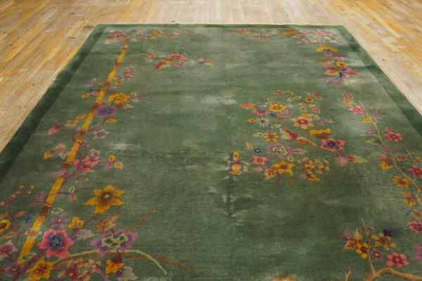 Green rug with multicolored flowers and yellow bamboo accents rests on light wooden plank flooring.