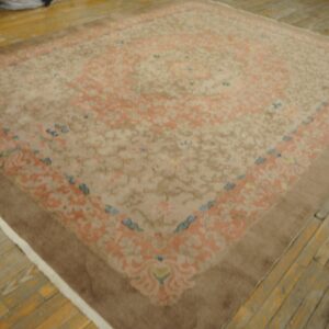 Traditional beige rug featuring peach and blue ornate patterns and a solid brown outer border on wood flooring.