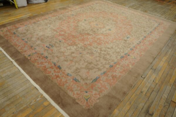 Traditional beige rug featuring peach and blue ornate patterns and a solid brown outer border on wood flooring.